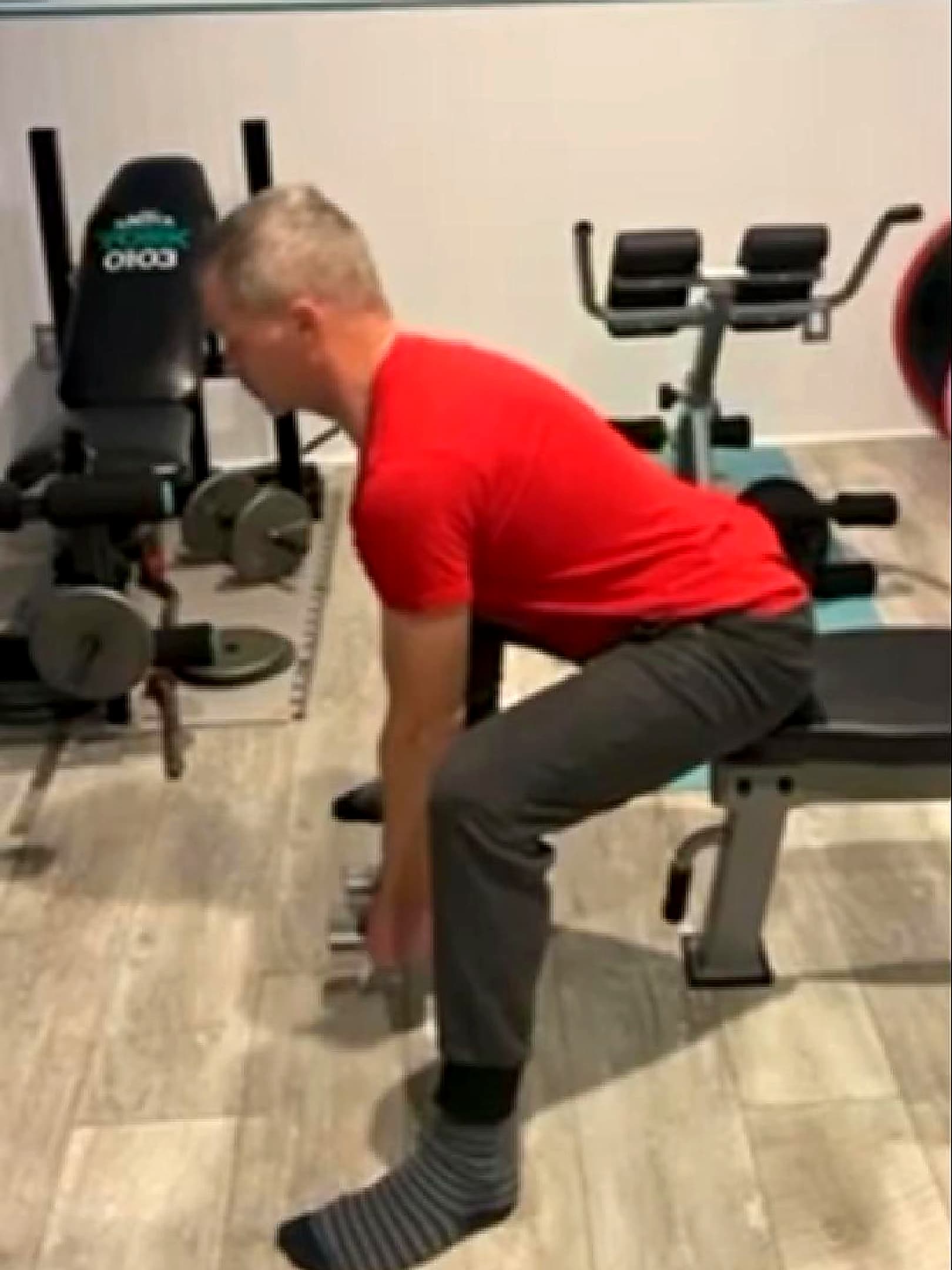 Client performing a seated good morning with a light dumbbell at the start of training